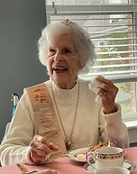 A companion wearing a tiara and sash at a celebration