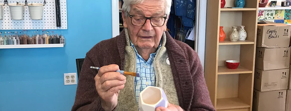 A companion painting pottery at a craft studio