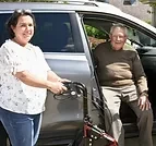 A Personal Care Assistant helping a companion out of a car