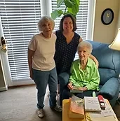 A Personal Care Assistant standing with two companions at home